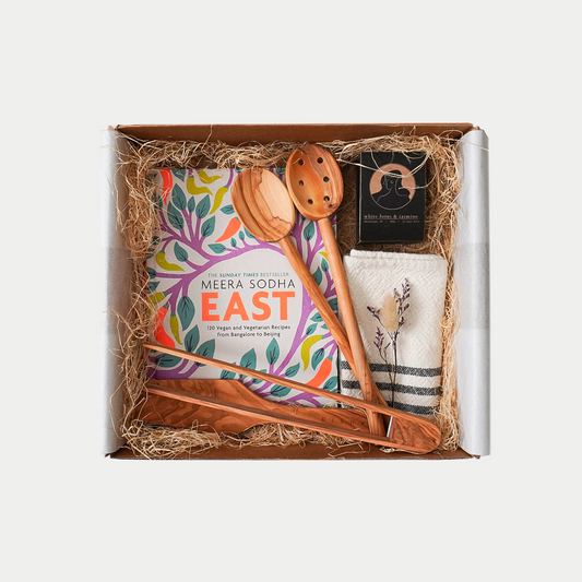 Gift Box - East recipe book by Meera Sodha, Olive wood oval spoon, Oval wood oval spoon with holes, Olive wood spatula, Olive wood thongs, Handwoven cotton tea towel, and Nōla candle white lotus and jasmine - hand crafted in New Zealand